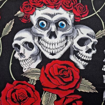 Tela de algodón tipo patchwork, con fondo negro y dibujos de calaveras y rosas rojas