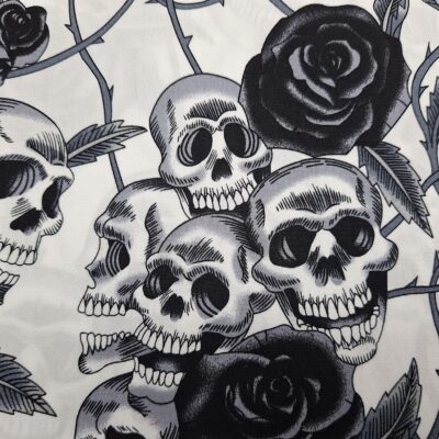 Tela de algodón tipo patchwork, con fondo blanco y dibujos de calaveras y rosas negras
