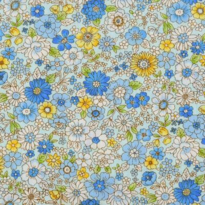 Tela de algodón tipo patchwork azul claro con flores en tonos azules y amarillos y hojas verdes