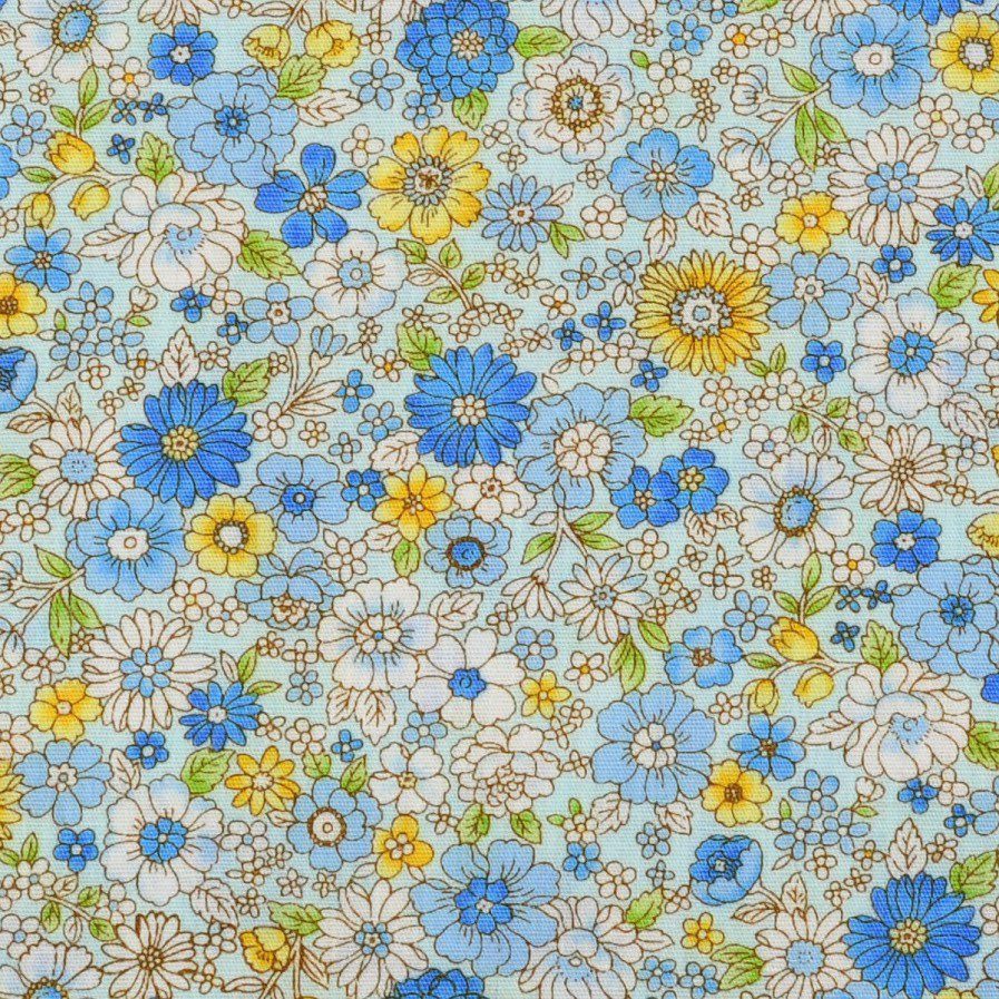 Tela de algodón tipo patchwork azul claro con flores en tonos azules y amarillos y hojas verdes