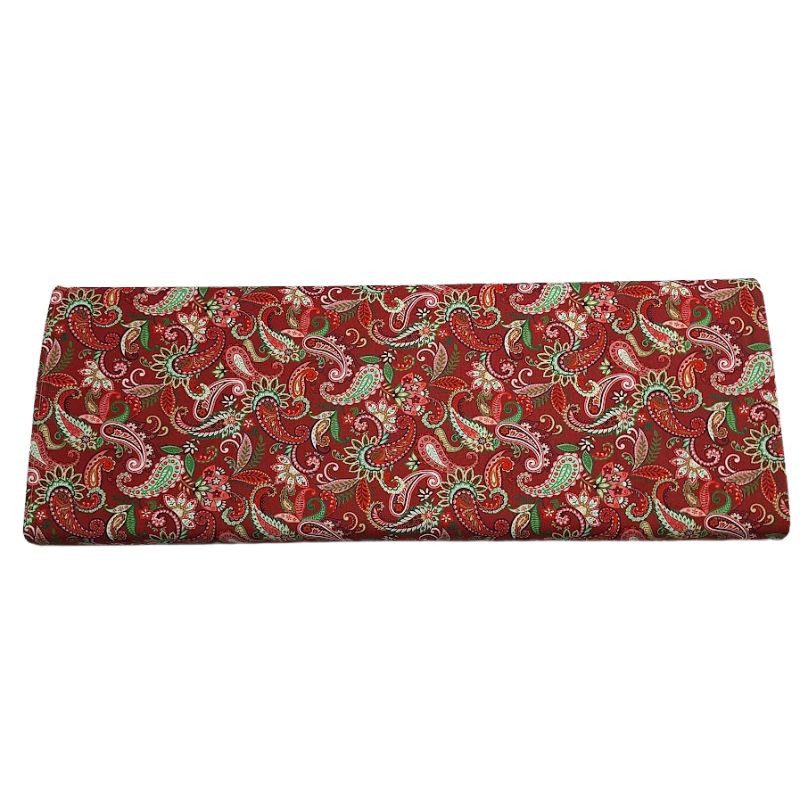 Tela de patchwork algodón 100% con estampado navideño de motivos de cachemir y detalles ornamentales en tonos verdes, rosas y cremas sobre un fondo rojo intenso de Studio E.